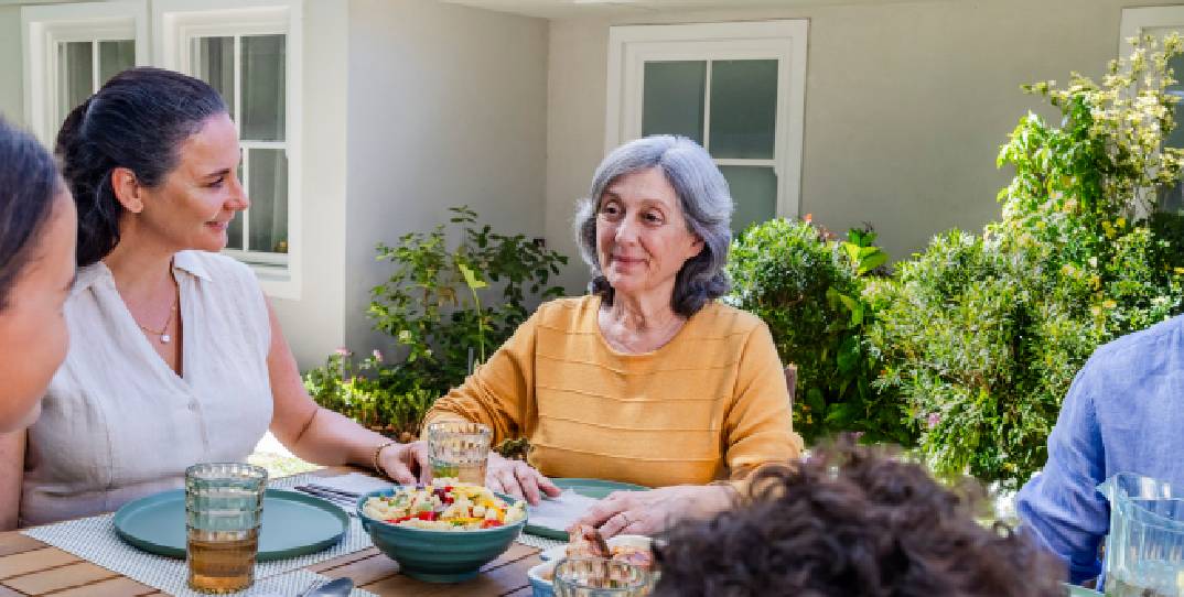 Representación actoral de una familia disfrutando de una cena al aire libre con su abuela quien vive con la agitación que puede ocurrir con la demencia debido a la enfermedad de Alzheimer.