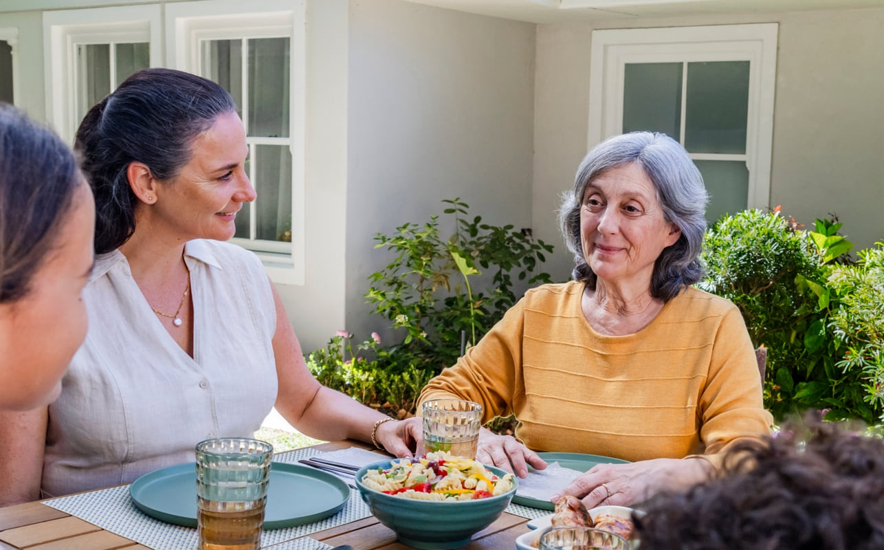 Representación actoral de una familia disfrutando de una cena al aire libre con su abuela quien vive con la agitación que puede ocurrir con la demencia debido a la enfermedad de Alzheimer.