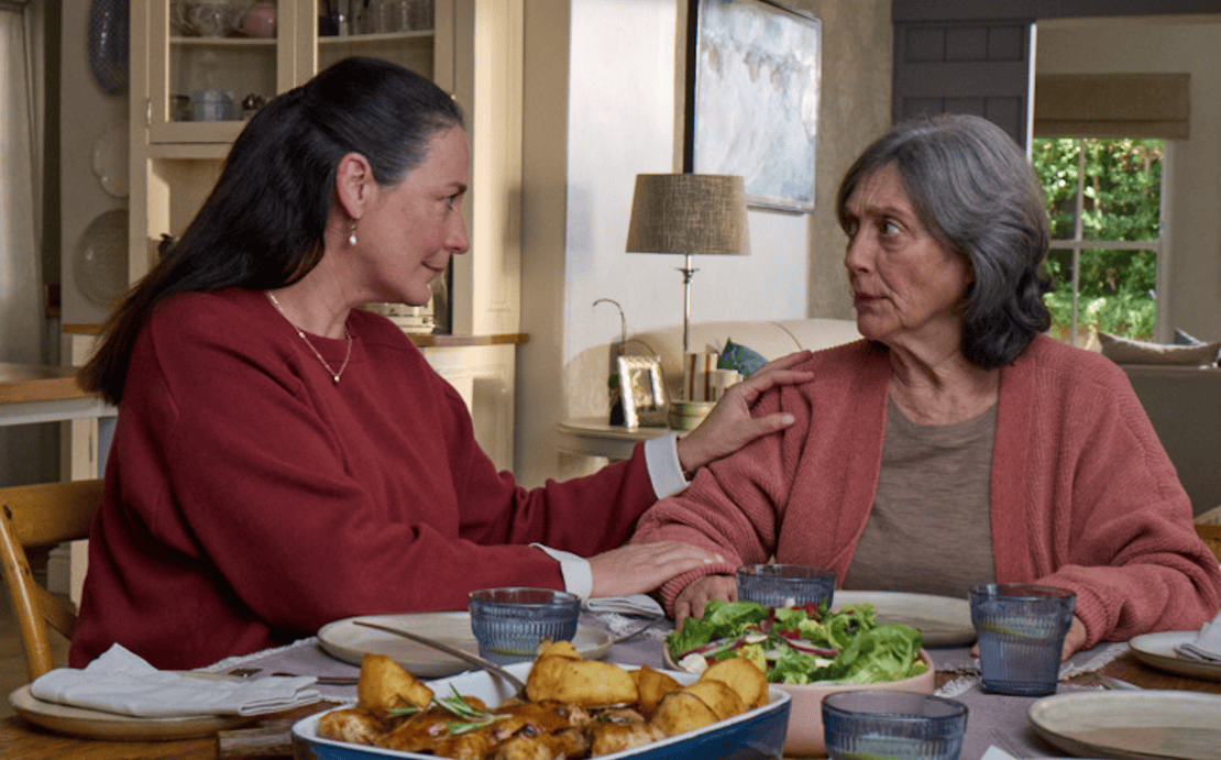 Actor portrayal of adult daughter comforting elderly mother over dinner who's living with agitation that may happen with dementia due to Alzheimer's disease.