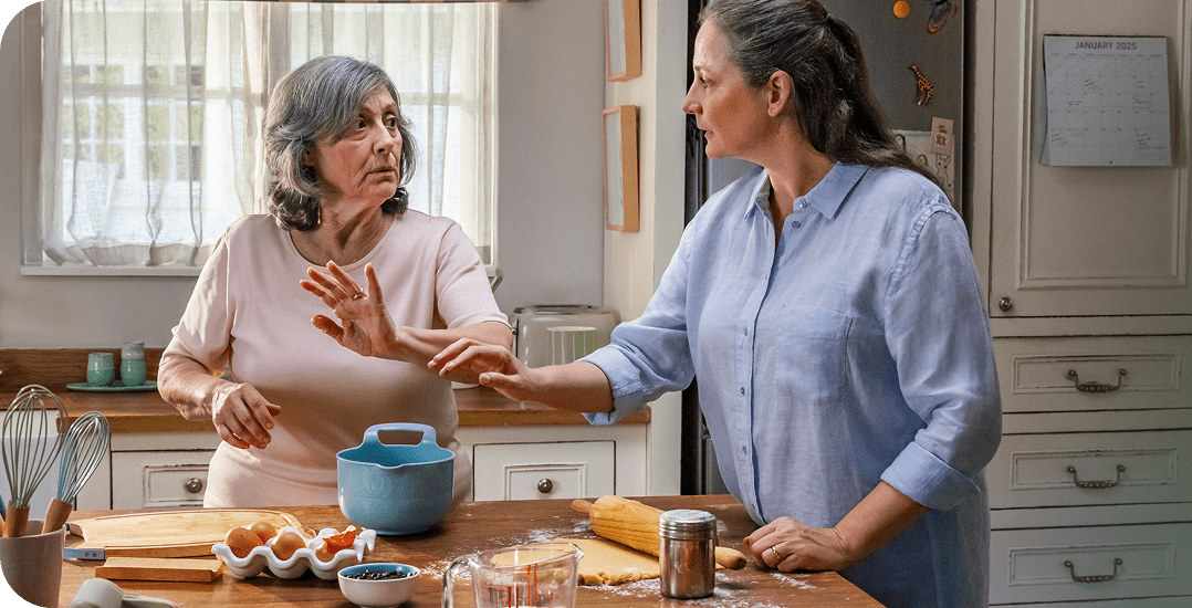 Representación actoral de una hija adulta consolando a su madre anciana en la cocina, quien vive con la agitación que puede ocurrir con la demencia debido a la enfermedad de Alzheimer.