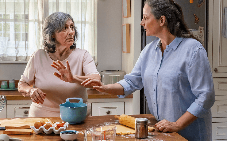 Representación actoral de una hija adulta consolando a su madre anciana en la cocina, quien vive con la agitación que puede ocurrir con la demencia debido a la enfermedad de Alzheimer.