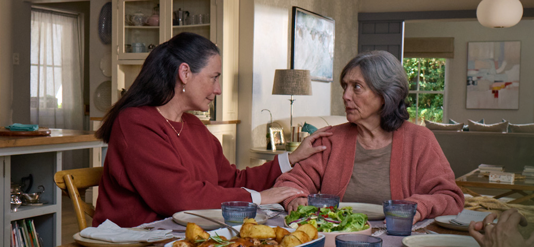 Actor portrayal of adult daughter comforting elderly mother over dinner who's living with agitation that may happen with dementia due to Alzheimer's disease.