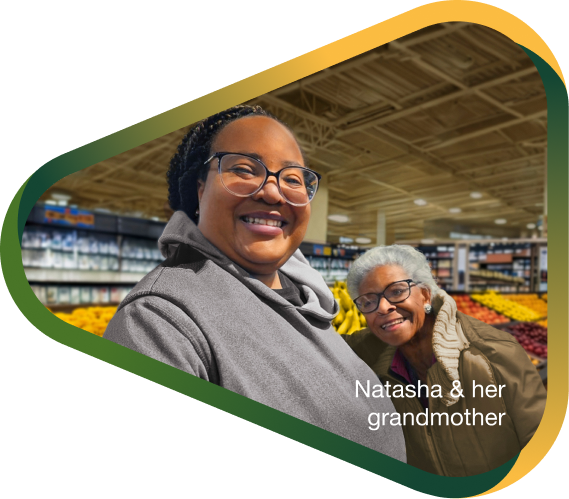 Caregiver Natasha and her grandmother with agitation that may happen with dementia due to Alzheimer's disease hugging and smiling in supermarket aisle.