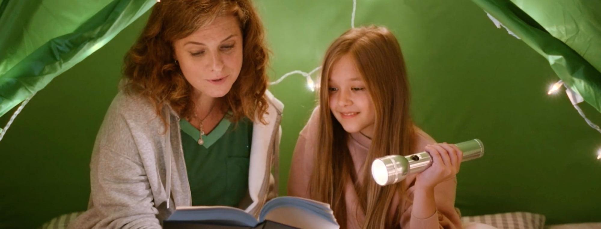 REXULTI for depression user reading with her daughter under a tent with a flashlight.