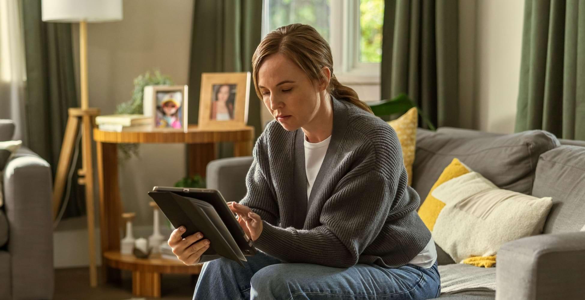 REXULTI for depression user looking at a tablet in her living room.